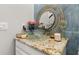 Close-up of a stylish vanity area with a glass vessel sink and marble countertop in the blue-tiled bathroom at 4952 Creekside Park Ave, Orlando, FL 32811
