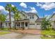 Charming two-story home featuring lush landscaping, a brick driveway, and a three-car garage at 4952 Creekside Park Ave, Orlando, FL 32811