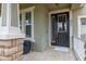 Close-up of the front porch with a black door, travertine tile and stone columns at 4952 Creekside Park Ave, Orlando, FL 32811