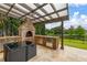 Outdoor kitchen with a brick pizza oven, grill, and countertop space by the water at 4952 Creekside Park Ave, Orlando, FL 32811