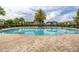 Community pool featuring brick perimeter, lounge chairs, palm trees, and shaded seating areas, perfect for relaxation at 4952 Creekside Park Ave, Orlando, FL 32811