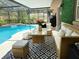 Screened-in patio with wicker furniture, patterned outdoor rug, and a view of the pool at 655 Vine Ct, Apopka, FL 32703