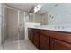 Bathroom featuring a large walk-in shower with glass door and double vanity with white countertop and dark wood cabinets at 6651 Syreeta Ln, Harmony, FL 34773