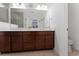 Bright bathroom featuring a double vanity with dark wood cabinets, a large mirror, and a separate toilet area at 6651 Syreeta Ln, Harmony, FL 34773