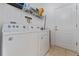 Well-lit laundry room featuring a white washer and dryer, tile floors, shelving, and a white door at 6651 Syreeta Ln, Harmony, FL 34773