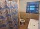 Modest bathroom featuring a window, toilet, and sink with blue and white shower curtain at 822 5Th St, Orlando, FL 32824