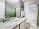 Well-lit bathroom with a granite countertop, modern faucet, and shower with green curtains at 824 Bloomingdale Dr, Davenport, FL 33897