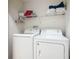 Practical laundry room features a stacked white washer and dryer with shelving above for storage at 824 Bloomingdale Dr, Davenport, FL 33897