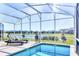 Screened in pool area with lounge chairs and a view of the surrounding community at 8974 Cabot Cliffs Dr, Davenport, FL 33896