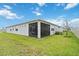 Rear view of the home featuring a screened patio and a lush lawn under a bright blue sky at 1895 Spring Shower Cir, Kissimmee, FL 34744