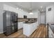 Well-appointed kitchen boasts stainless steel refrigerator, white cabinetry, granite countertops, and a central island at 1236 Aquila Loop, Celebration, FL 34747