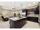 Open-concept kitchen with dark cabinets, stainless steel appliances, and granite island connected to the living area at 1592 Castile St, Celebration, FL 34747