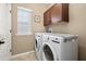 Convenient laundry room equipped with a washer, dryer, and overhead cabinets for ample storage at 1592 Castile St, Celebration, FL 34747