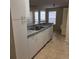 A compact kitchen featuring white cabinetry, a stainless steel sink, and a view into the living area at 1608 Columbia Arms Cir # 126, Kissimmee, FL 34741