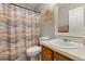 Bright bathroom showcasing a patterned shower curtain, a toilet, and a sink with wooden cabinets at 1704 Pine Ridge Dr, Davenport, FL 33896