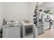Laundry room with modern washer and dryer, leading into a kitchen with stainless steel appliances and white cabinets at 1704 Pine Ridge Dr, Davenport, FL 33896