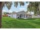 Backyard view of a single-story house with a screened patio, grass, and a fenced perimeter at 2700 Palm Isle Way, Orlando, FL 32829