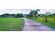 Long driveway leading to a beautiful home, surrounded by lush green lawns and mature palm trees at 2851 Granada Blvd, Kissimmee, FL 34746