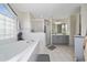 Bright bathroom featuring a large tub, glass-enclosed shower, and double sink vanity at 3161 Timberly Ln, Lakeland, FL 33810