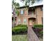 Charming townhouse featuring a brick walkway, lush landscaping, and a cozy second-story balcony at 324 Palermo St, Davenport, FL 33897
