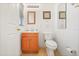 Cozy bathroom with a light colored vanity, toilet, decorative mirror, and framed artwork at 3335 Whistling Trl, St Cloud, FL 34772