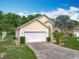 Beautiful tan one story home with a two car garage, lush landscaping, and a large driveway at 341 Whittier St, Davenport, FL 33896
