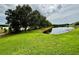 Lush backyard with a serene pond view, framed by mature trees and vibrant green grass at 4368 Fox Glen Loop, Kissimmee, FL 34746