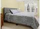 Bedroom features neutral walls, a queen bed with gray linens, and natural light from a window with sheer white curtains at 516 Millifiora Ln, Kissimmee, FL 34759