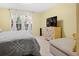 This bright bedroom features a queen bed, a colorful dresser, a TV and a window with natural light at 516 Millifiora Ln, Kissimmee, FL 34759