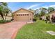 Well-maintained home with a brick driveway, verdant lawn, and a neutral-toned exterior at 516 Millifiora Ln, Kissimmee, FL 34759