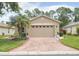 Charming single-story home featuring a brick driveway, lush landscaping, and a welcoming front facade at 516 Millifiora Ln, Kissimmee, FL 34759