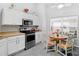 Cozy eat-in kitchen featuring stainless steel appliances, white cabinetry and a round dining table with colorful chairs at 516 Millifiora Ln, Kissimmee, FL 34759