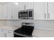 A close up of stainless appliances in a kitchen with white quartz counters and cabinets at 545 Summit River Dr, Apopka, FL 32712