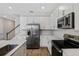 A modern kitchen with white cabinets, stainless appliances, and wood-look tile at 545 Summit River Dr, Apopka, FL 32712