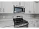 Close-up of a modern range and microwave with white cabinets and quartz countertops at 555 Summit River Dr, Apopka, FL 32712