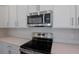 Close-up of kitchen featuring stainless steel oven, cooktop, microwave, and white cabinets at 565 Summit River Dr, Apopka, FL 32712