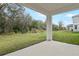 Covered patio overlooking a grassy backyard surrounded by trees and partial views of neighboring houses at 565 Summit River Dr, Apopka, FL 32712