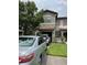 View of the townhome exterior featuring a front lawn, driveway, and two parked cars at 5930 Tivoli Gardens Blvd, Orlando, FL 32829