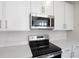 Close-up of kitchen appliances featuring stainless steel microwave and a black electric stove top and range at 640 Summit River Dr, Apopka, FL 32712