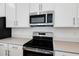 A close-up of a stainless steel microwave and electric range featured with white cabinets and stone countertops at 675 Summit River Dr, Apopka, FL 32712