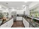 A modern kitchen with white cabinets, black countertops, and stainless steel appliances at 736 Forest Glen Ct, Maitland, FL 32751