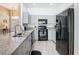 Contemporary kitchen showcasing stainless steel sink, granite countertops, and black appliances, with light gray cabinets at 116 Westport Ln, Davenport, FL 33896
