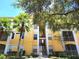 Inviting yellow condo building featuring well-maintained landscaping and a calming atmosphere with mature trees and clear blue skies at 1325 Lake Shadow Cir # 12205, Maitland, FL 32751