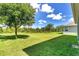 Expansive backyard with lush lawn, mature trees, and clear blue skies offers endless possibilities for outdoor enjoyment at 1856 Castleton Dr, St Cloud, FL 34771