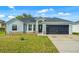 Charming single-story home with a well-maintained lawn, a dark roof, and attached two-car garage at 1913 Manatee Ct, Kissimmee, FL 34759