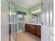 Bathroom featuring a glass-enclosed shower, dual vanities, a large mirror, and soft green walls at 214 Verona Dr, Kissimmee, FL 34759