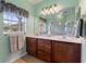 Bathroom showcasing dual sinks, a large mirror, a window, and a glass-door shower at 214 Verona Dr, Kissimmee, FL 34759