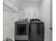 Efficient laundry room with modern washer and dryer, plus overhead shelving for storage at 2561 Montego Bay Blvd, Kissimmee, FL 34746