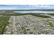 An aerial view shows the neighborhood with stunning lake and wooded views in the background at 2838 Common Crane Ct, Harmony, FL 34773