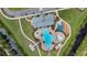 Top-down aerial shot of community pool with playground, clubhouse, parking and surrounding greenery at 2838 Common Crane Ct, Harmony, FL 34773